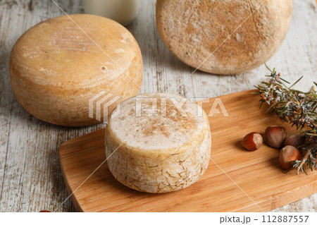 Artisanal and natural whole cheese, placed on a wooden board and without labels. 112887557