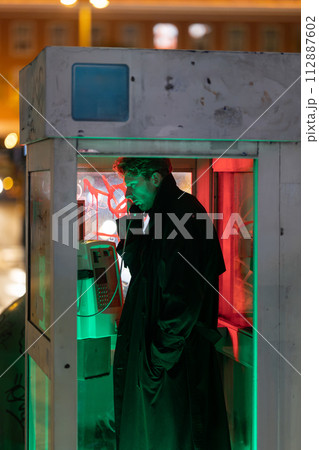 A man is talking on a phone in a booth 112887602