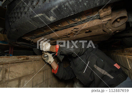 Machine maintenance and engine oil changes. Repairing a car in the garage with your own hands. Scheduled car maintenance in a pit garage. Machine maintenance and engine oil changes. Repairing a car in the garage with your own hands. Scheduled car maintenance in a pit garage. 112887659