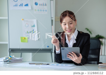 Business woman using tablet and laptop for doing math finance on an office desk, tax, report, accounting, statistics, and analytical research concept in office  112888112