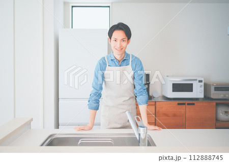 キッチンに立つエプロン姿の男性 キッチンに立つエプロン姿の男性 112888745