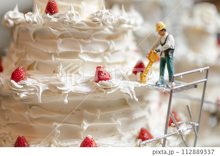ミニチュアフィギュアがデコレーションする苺のショートケーキ 112889337