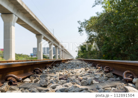 Closeup of railway track, a shallow depth of field focusing on the railroad ties and rocks on the track. Metal rails are fastened to the ties with clips or spikes, which help keep the rails in place. Closeup of railway track, a shallow depth of field focusing on the railroad ties and rocks on the track. Metal rails are fastened to the ties with clips or spikes, which help keep the rails in place. 112891504