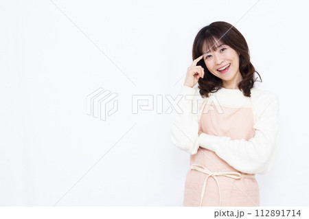 笑顔で考えているエプロン姿の主婦 112891714