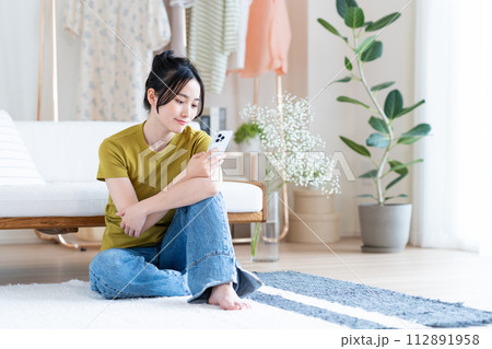 リビングでスマホを見る若い女性 リビングでスマホを見る若い女性 112891958