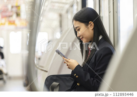 電車の中でスマートホンの画面を見る女子高校生　電車通学　イメージ 112893446