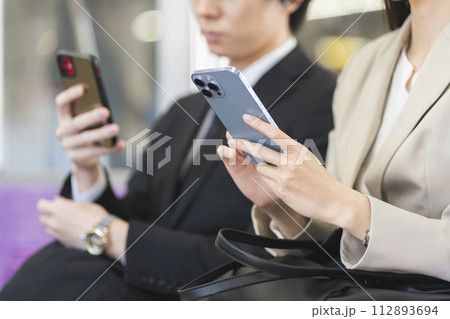 電車の中でスマートフォンを操作するビジネスウーマンの手元 電車の中でスマートフォンを操作するビジネスウーマンの手元 112893694