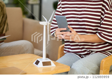 Cropped image of woman photographing model of wind turbine 112893959