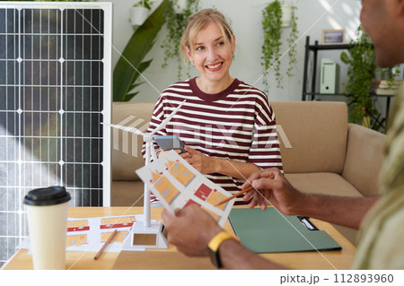 Smiling woman listening to manager explaining benefits of solar panel system Smiling woman listening to manager explaining benefits of solar panel system 112893960
