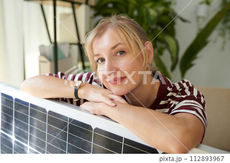 Portrait of woman leaning on solar panel and smiling at camera Portrait of woman leaning on solar panel and smiling at camera 112893967