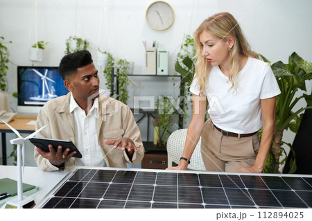 Diverse team of engineers discussing solar panel output Diverse team of engineers discussing solar panel output 112894025