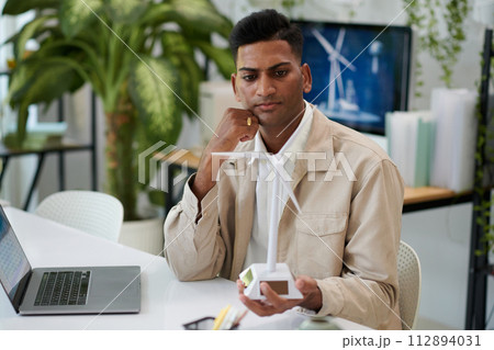 Serious contemplating engineer looking at improved model of wind turbine 112894031