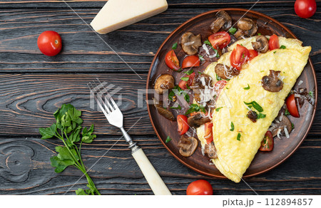 Omelette stuffed with mushrooms , tomatoes and parsley 112894857