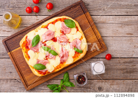 Traditional italian pizza with ham mozzarella and basil Traditional italian pizza with ham mozzarella and basil 112894898