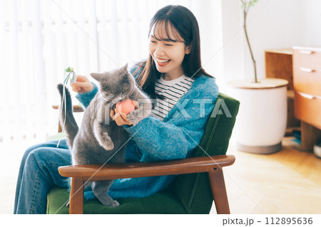 自宅で猫と遊ぶ女性 112895636
