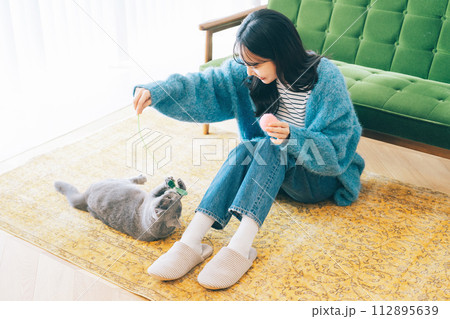 自宅で猫と遊ぶ女性 112895639