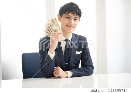 現金を手にして喜ぶビジネスマン 112895714