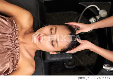 Clam relaxed woman getting her hair rinsed after hair wash 112896375