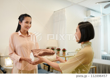 Wax salon worker giving client fresh towels Wax salon worker giving client fresh towels 112896457