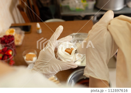 The pastry chef decorates the tiramisu in a glass with whipped cream. 112897616
