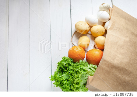 Paper bag on a wooden background, vegetables from the store Paper bag on a wooden background, vegetables from the store 112897739