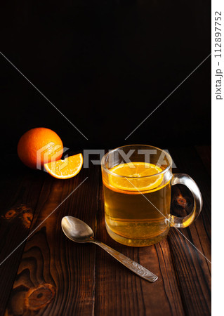 Tea with orange, sprinkled sugar, sliced orange, wooden brown backgroun 112897752