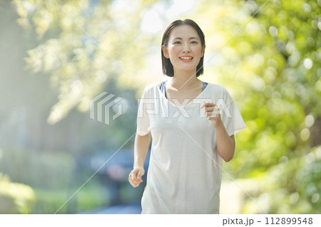 スポーツウエアでランニングをする笑顔の若い女性 スポーツウエアでランニングをする笑顔の若い女性 112899548