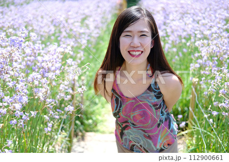 Beautiful Asian woman is smiling and relaxing in blooming purple Murdannia giganteum flowers field 112900661