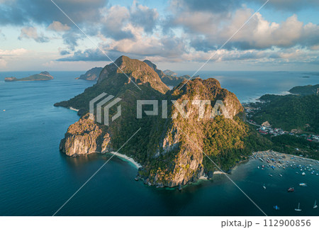 Aerial view of beach, sea and mountain on sunset. El Nido, Palawan. Tropical landscape hill, mountains rocks with rainforest and azure water of lagoon. Aerial view of beach, sea and mountain on sunset. El Nido, Palawan. Tropical landscape hill, mountains rocks with rainforest and azure water of lagoon. 112900856