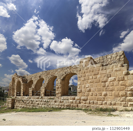 Roman ruins (against the background of a beautiful sky with clouds) in the Jordanian city of Jerash (Gerasa of Antiquity), capital and largest city of Jerash Governorate, Jordan 112901449