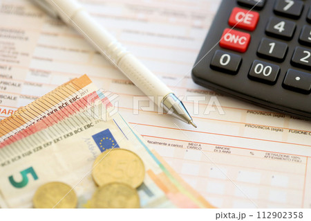 Filling italian tax form process with pen, calculator and euro money bills close up. Tax paying period and deadline Filling italian tax form process with pen, calculator and euro money bills close up. Tax paying period and deadline 112902358