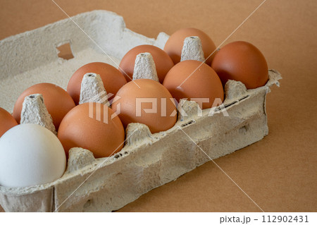 Fresh chicken eggs in a paper tray on the table, selective focus 112902431