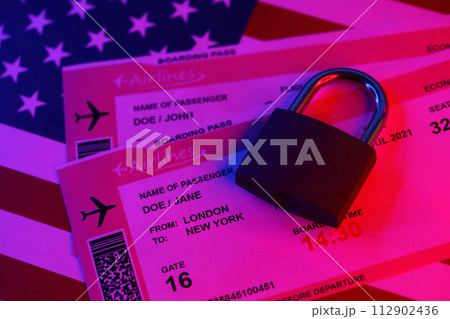Fictional air tickets and small padlock on United States of America flag close up 112902436