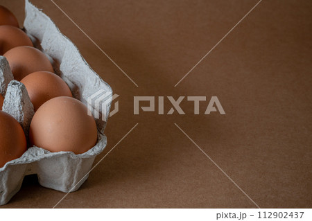 Fresh chicken eggs in a paper tray on the table, selective focus 112902437