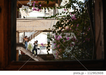 Young man photographing girlfriend on steps of abandoned building Young man photographing girlfriend on steps of abandoned building 112902608