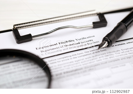 I-9 Employment Eligibility Verification blank form on A4 tablet lies on office table with pen and magnifying glass close up 112902987