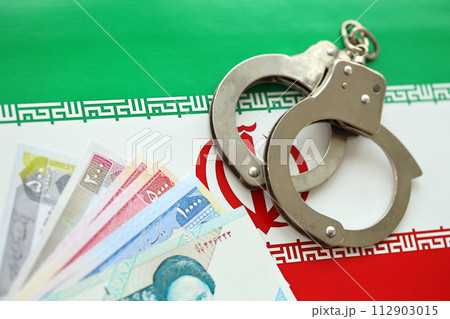 Iran flag and police handcuffs with iranian money bills rials. The concept of crime and offenses in the country 112903015