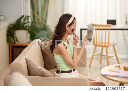 Teenage girl applying makeup when getting ready in the morning 112903217