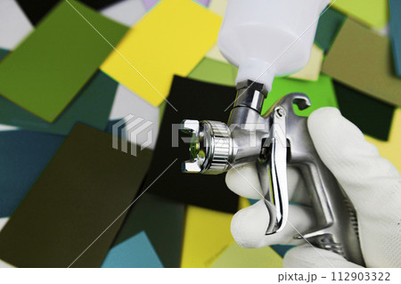 paint spray gun at work at the workplace in the workshop, selection of tools, paint samples paint spray gun at work at the workplace in the workshop, selection of tools, paint samples 112903322