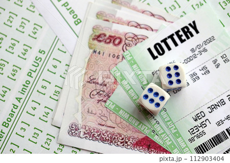 Green lottery tickets and Great Britain pounds money bills on blank with numbers for playing lottery close up 112903404
