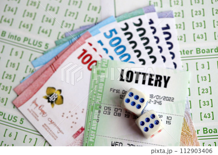 Green lottery tickets and indonesian money bills on blank with numbers for playing lottery close up Green lottery tickets and indonesian money bills on blank with numbers for playing lottery close up 112903406