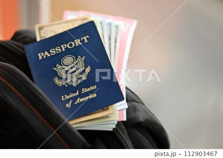 Blue United States of America passport with money and airline tickets on touristic backpack close up. Tourism and travel concept Blue United States of America passport with money and airline tickets on touristic backpack close up. Tourism and travel concept 112903467