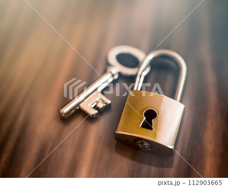 Metal padlock with a key on blurred background. Security and protection concept. 112903665