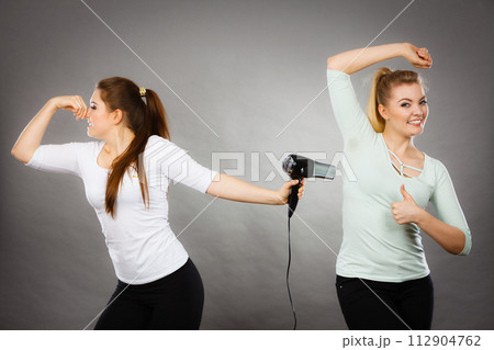 Woman drying friend armpit with hair dryer 112904762