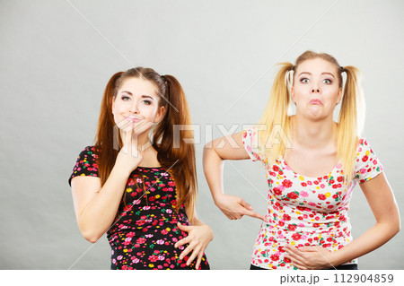 Two cheerful teenage woman holding their stomach Two cheerful teenage woman holding their stomach 112904859
