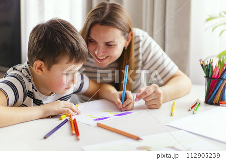 Mother and son drawing together with colorful pencils. Mother and son drawing together with colorful pencils. 112905239