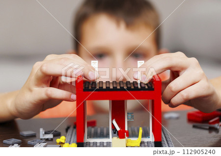 Child building a red toy structure with blocks on a table Child building a red toy structure with blocks on a table 112905240