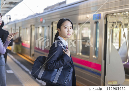 駅のホームで電車を待つ女子高校生 112905482