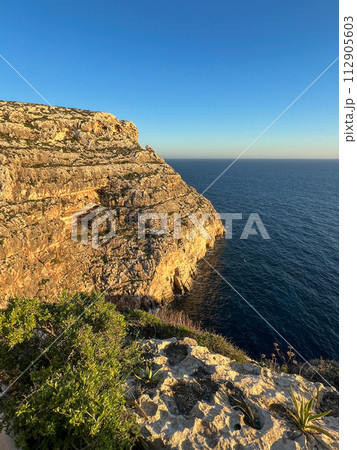 Wied iz-Zurrieq harbour and Blue Grotto sea caves are located on the coastline opposite to the small islet of Filfla. Wied iz-Zurrieq harbour and Blue Grotto sea caves are located on the coastline opposite to the small islet of Filfla. 112905603