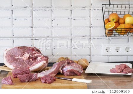 Different tipes of meat, cutting fresh raw meat on board in white kitchen. Preparing pork meat, cooking Different tipes of meat, cutting fresh raw meat on board in white kitchen. Preparing pork meat, cooking 112909169